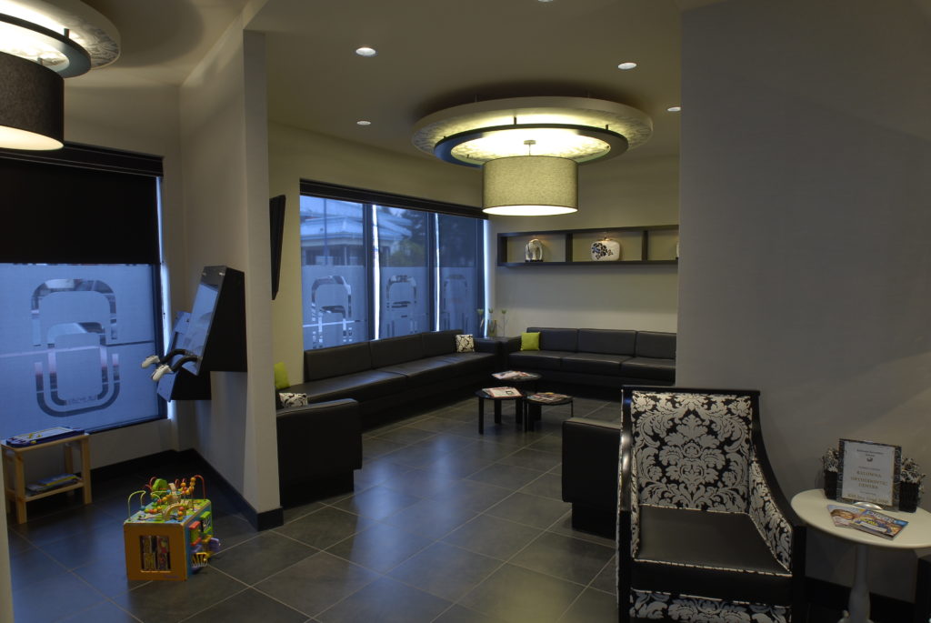 Waiting area and kids plat area with dark wood floors and white walls at Kelowna Orthodontics.