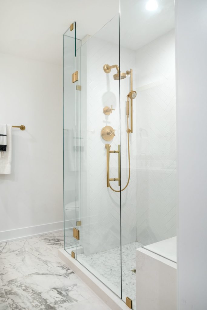White glass door shower with gold fixtures in lakefront luxury BC home.