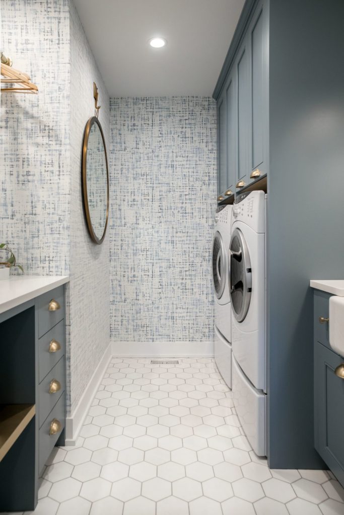 Luxury laundry room renovation with white walls and floors, and grey cabinets.