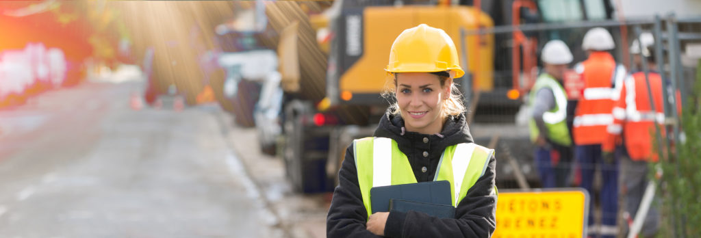 panoramic view of young female construction worker with a building team in the background