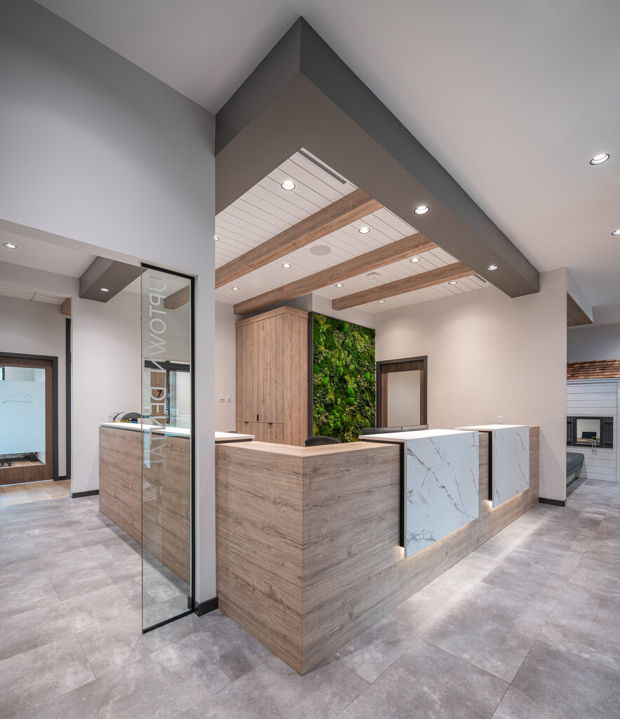 the reception desk at Uptown Dental in Salmon Arm, with natural elements like walnut doors, concrete floor tiles and quartz accented reception desk